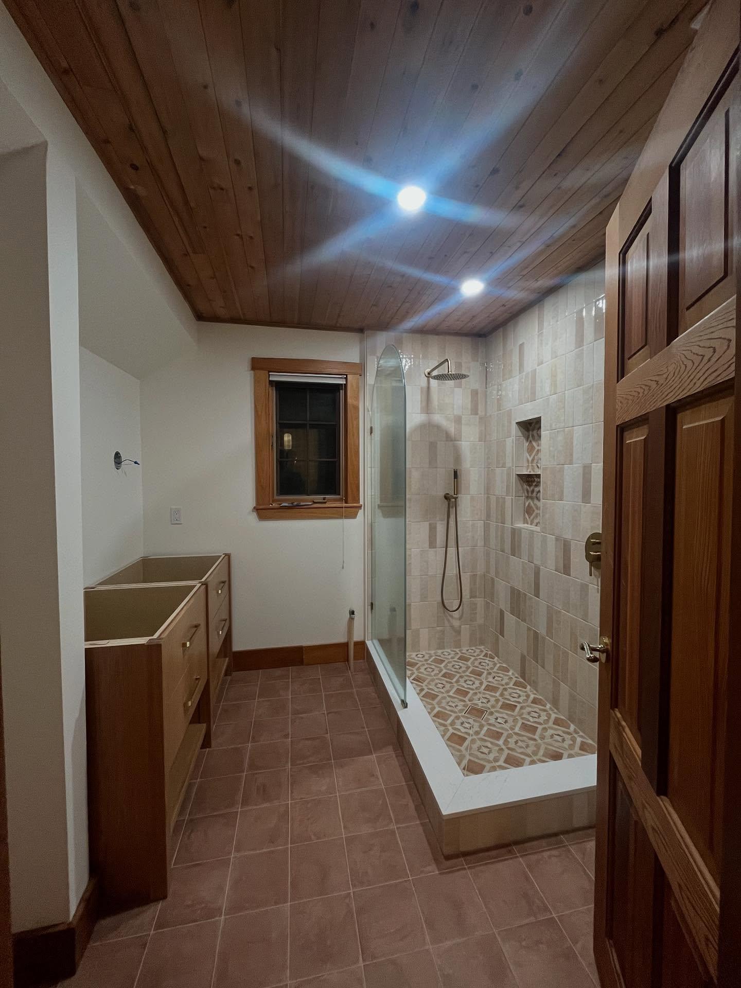 Ensuite with glass shower, patterned shower floor and cedar ceiling